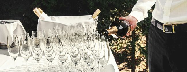 A birthday cake with lit candles and sprinkles, plus a pair of hands nearby, in a cozy, celebratory setting.