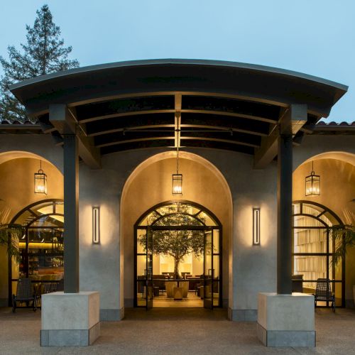 A building with a grand entrance and warm lights; stone arches frame glass doors, inviting interior displays.
