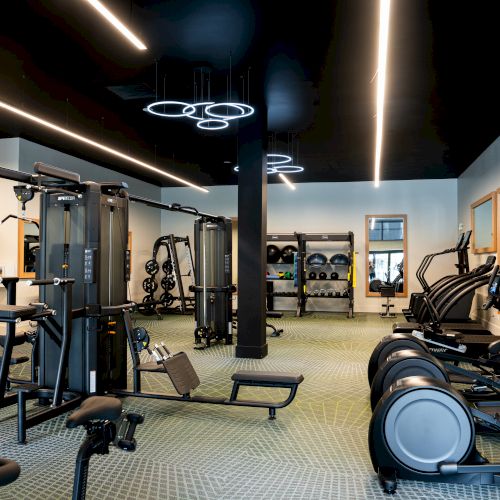 A modern gym with treadmills, weight machines, free weights, and a spacious, well-lit workout area ending this sentence.