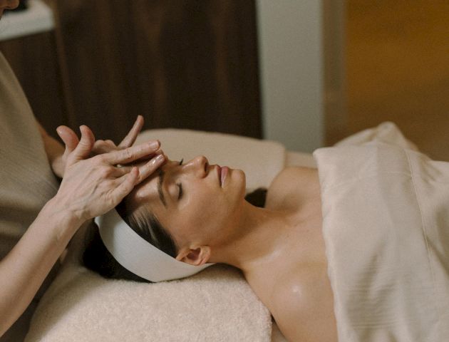 I can&rsquo;t identify people in images, but it shows a woman lying in bed with a hand near her face, wearing a light top.