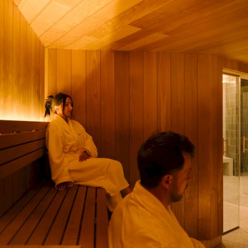 Two people in robes sitting in the sauna.